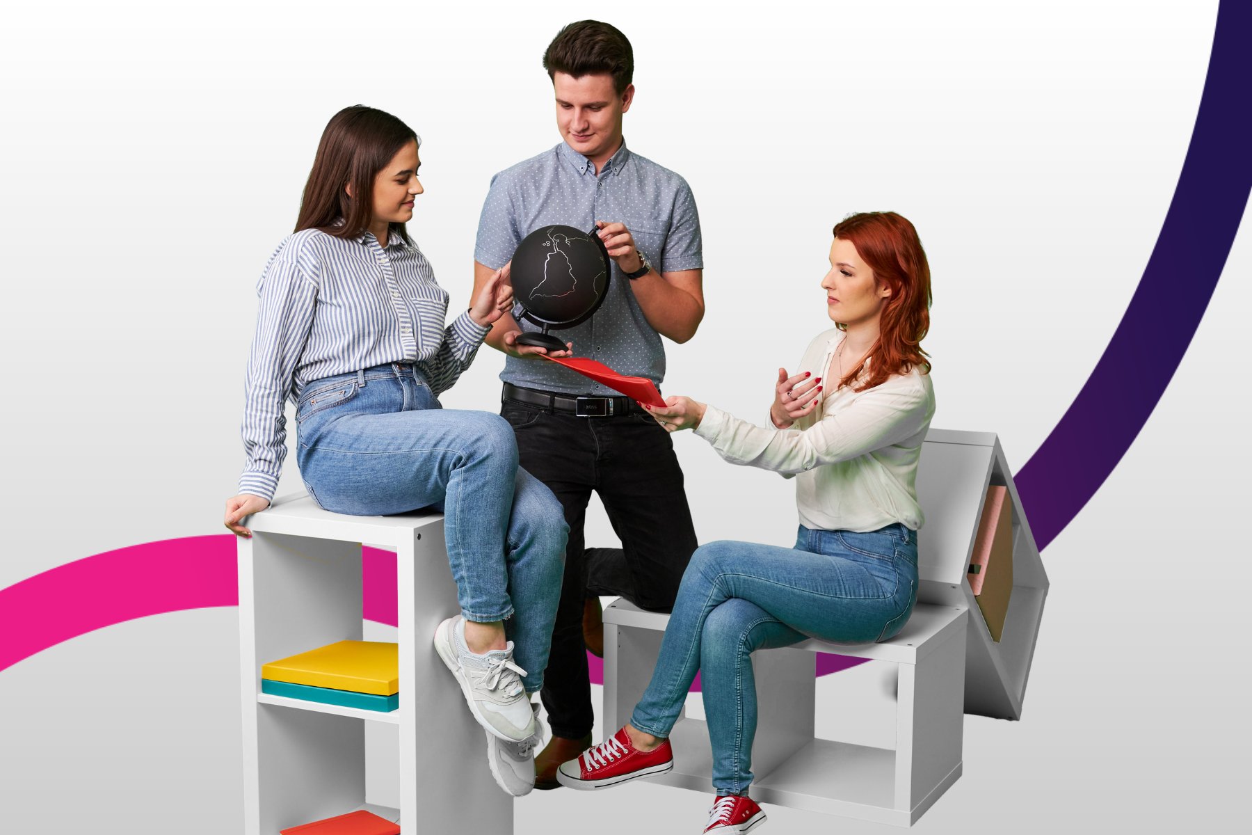 Trójka studentów dwie dziewczyny siedzą po środku stoi chłopak z czarnym globusem