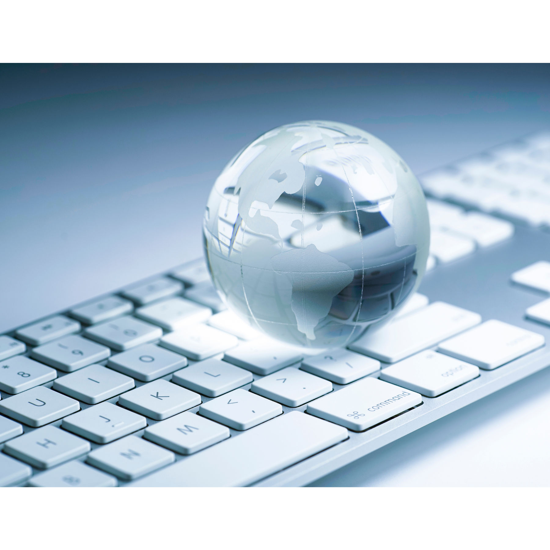 Szklana kula ziemska położona na nowoczesnej klawiaturze komputerowej, wszystko zachowane w odcieniach niebieskiego i szarego