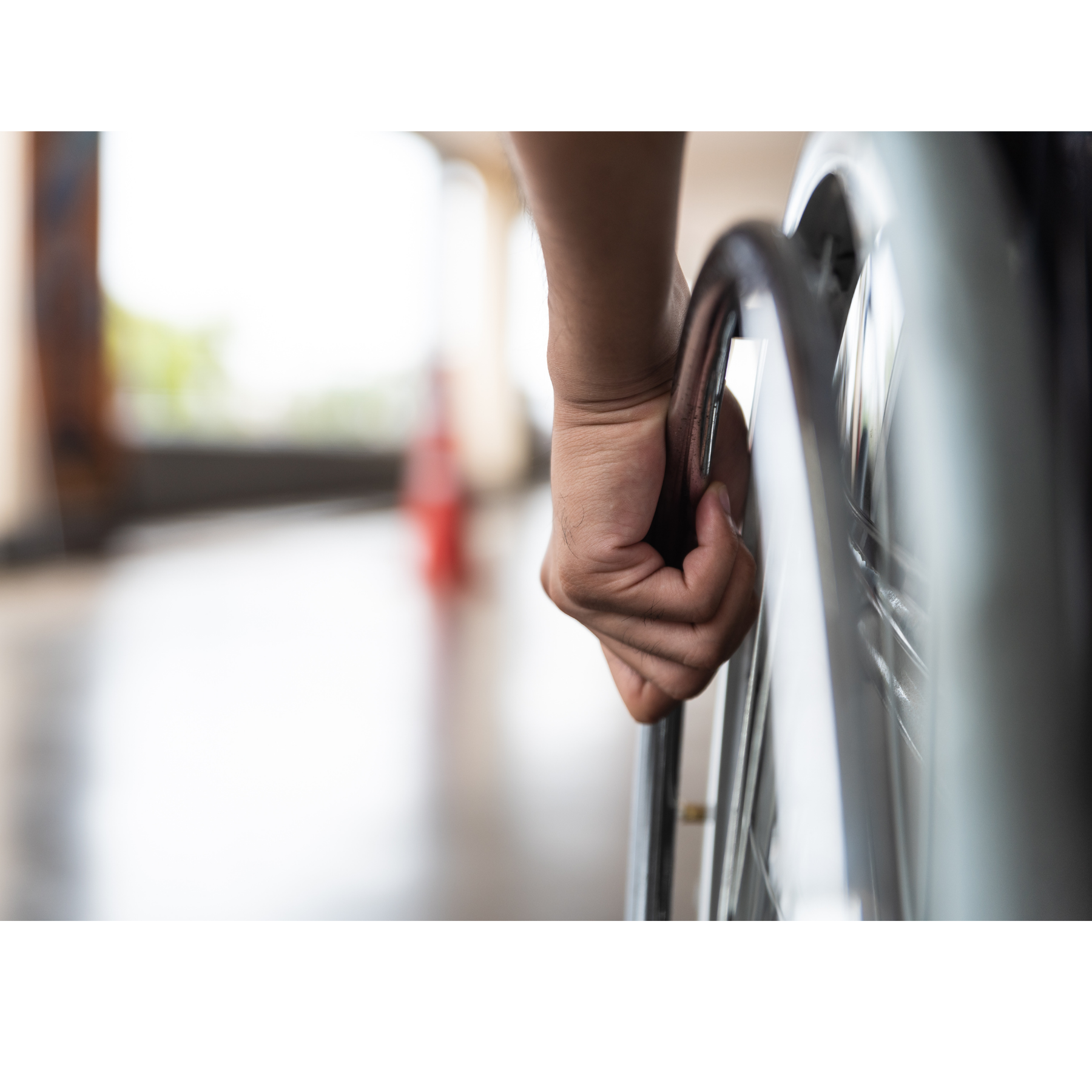 ręka trzymająca za koło wózka dla osób z niepełnosprawnością