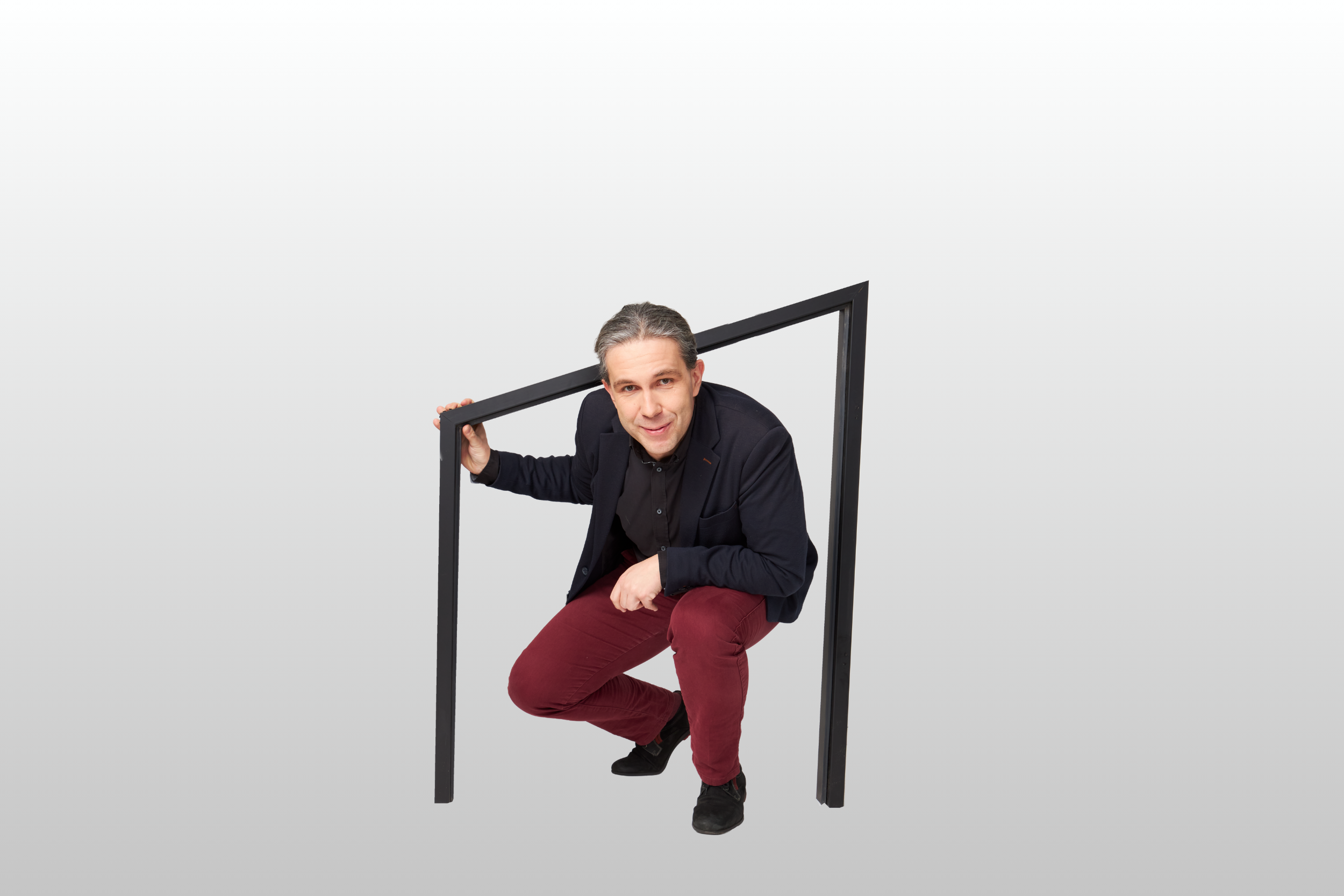 Elegancko ubrany mężczyzna kuca i lekko się uśmiecha