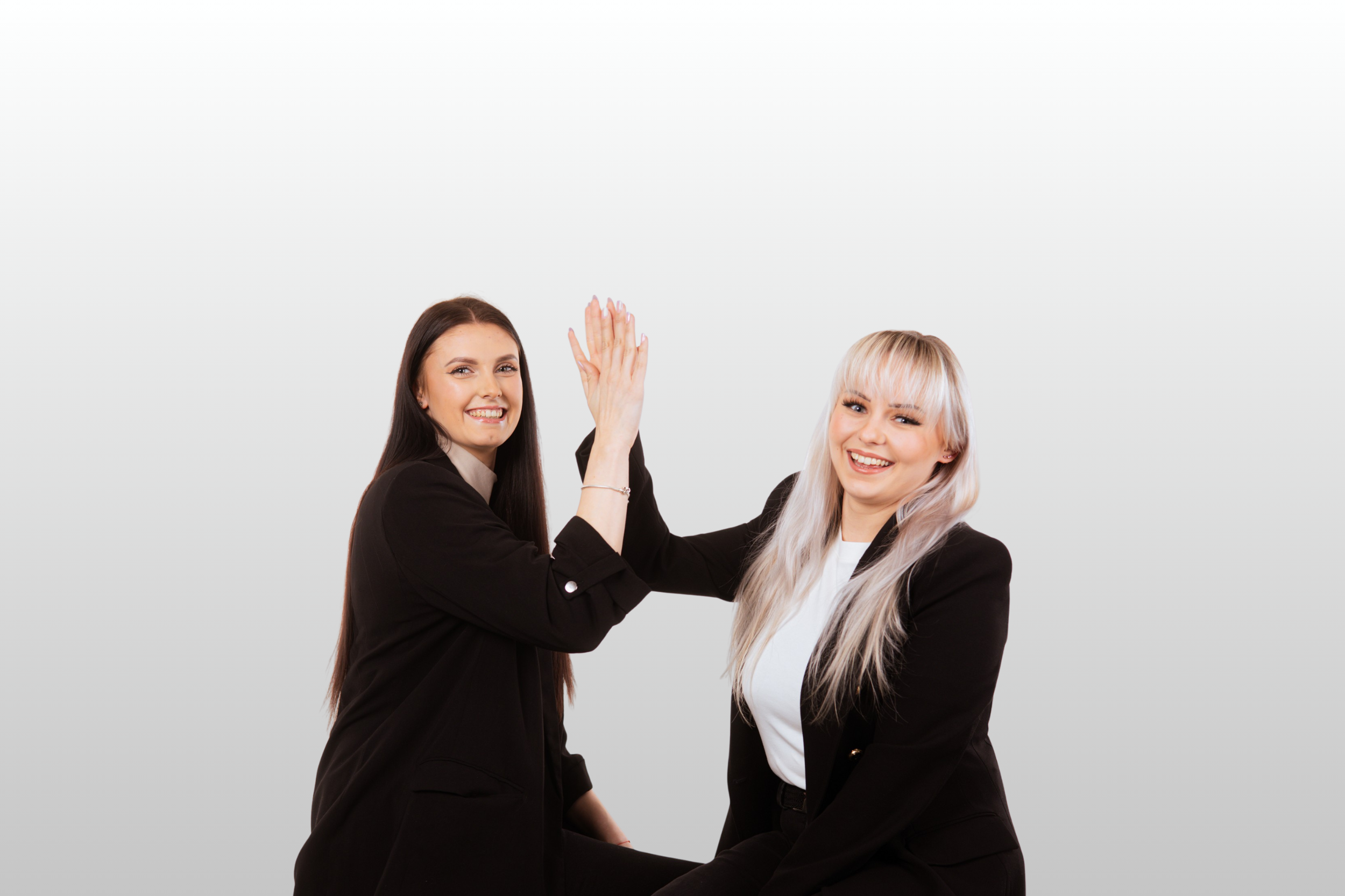 Dwie dziewczyny studentki, blondynka i brunetka przybijają sobie "piątkę" jed