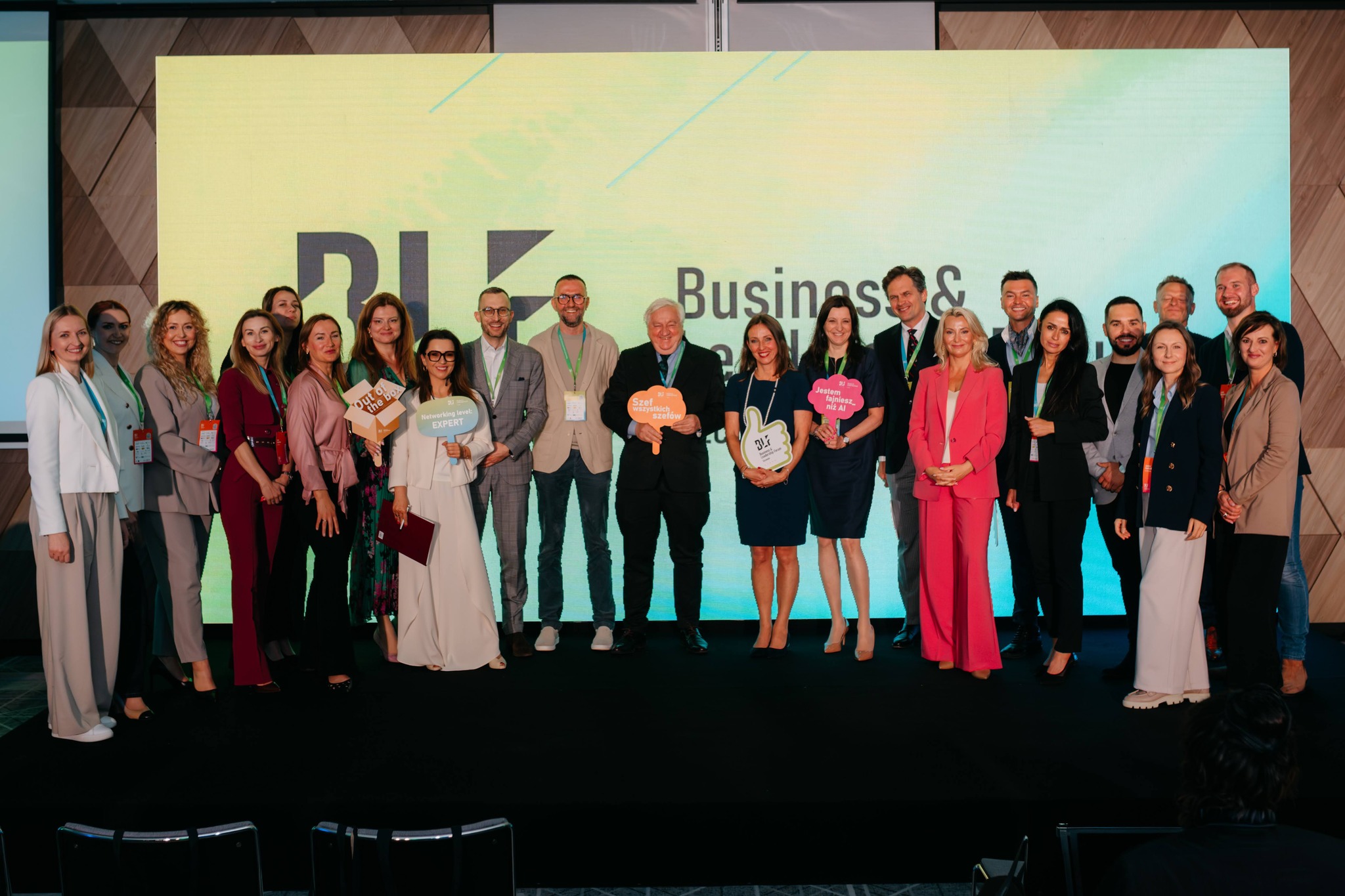 Grupa ludzi stojąca na scenie - to osoby biorące udział w konferencji.