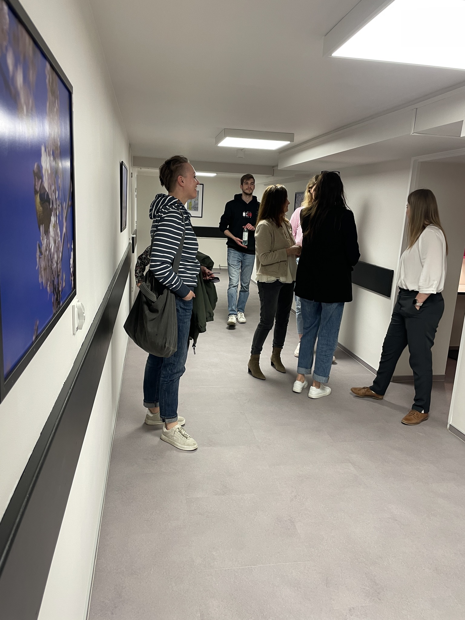 Rozmawiająca grupa studentów i wykładowców w korytarzu